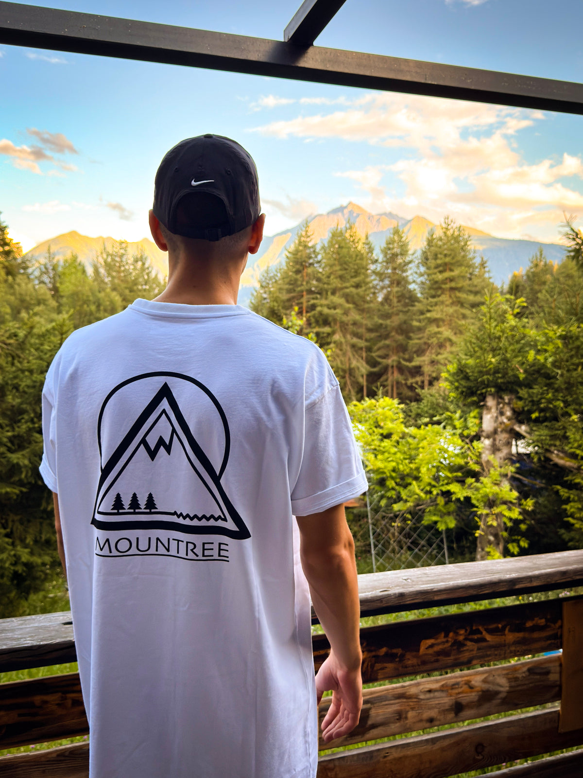 Quirin im MOUNTREE Original Logo Tee White mit großem Mountain Logo vor Bergkulisse