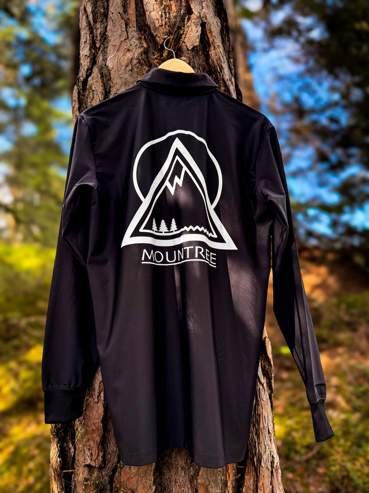 MOUNTREE Tech Polo Longsleeve Black – Rückansicht mit großem Mountain Logo im Wald